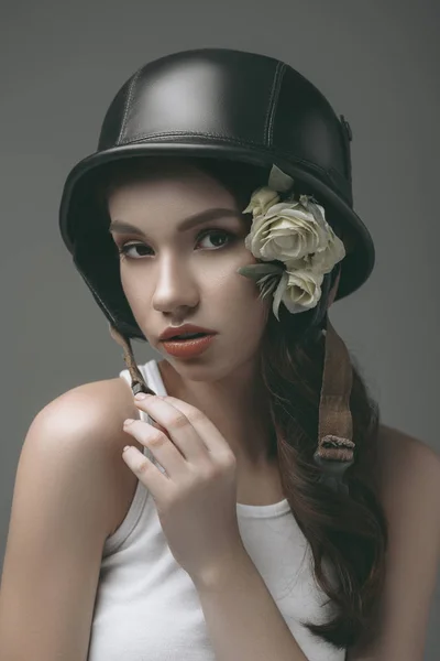 Привлекательная девушка в военном шлеме с цветами, изолированная на сером — стоковое фото