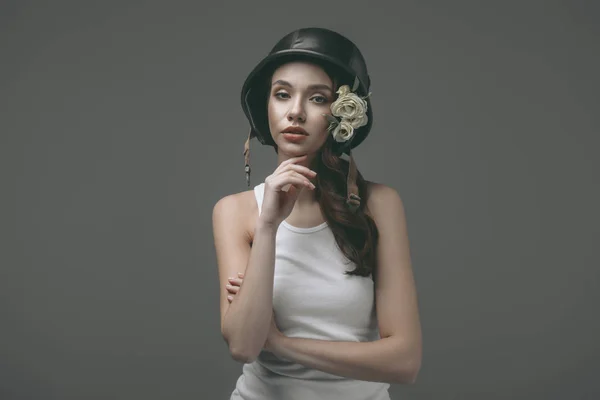 Beautiful young girl in military helmet with flowers, isolated on grey — Stock Photo