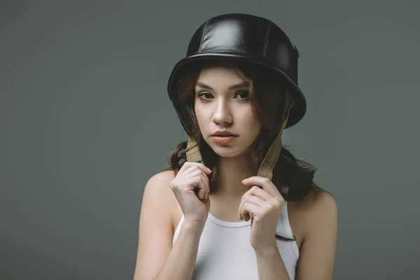 Стильная молодая девушка в военном шлеме, изолированная на сером — стоковое фото