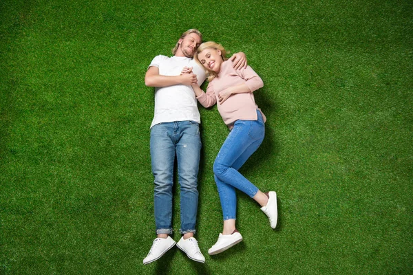 Pregnant woman with boyfriend lying on grass — Stock Photo, Image