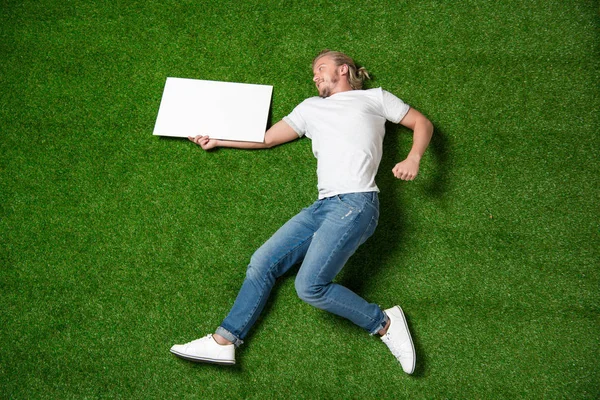 Man with blank placard on grass