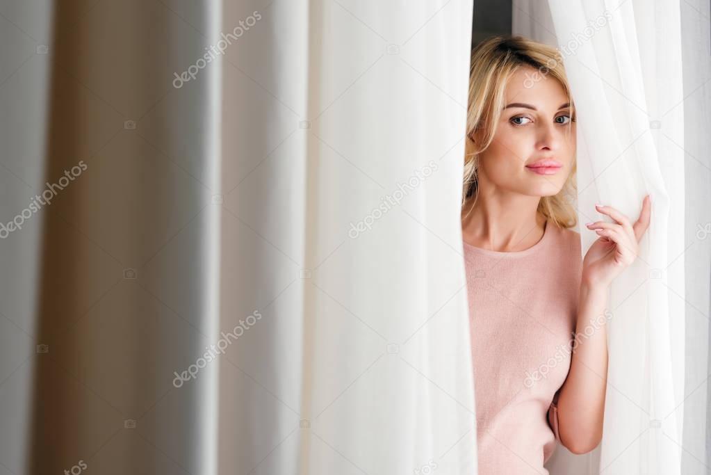 woman looking out of curtain