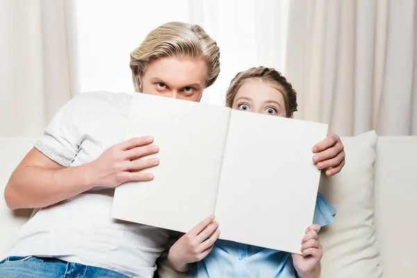 Pai e filha cobrindo rosto com livro — Fotografia de Stock