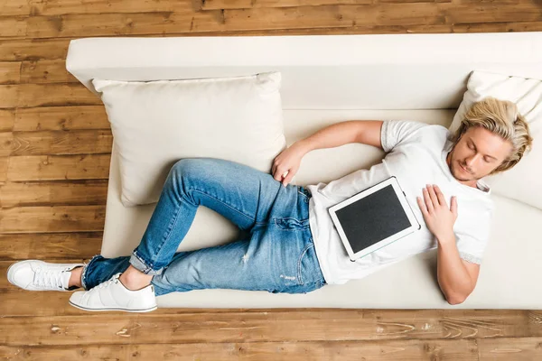 Человек спит на диване с цифровым планшетом — стоковое фото