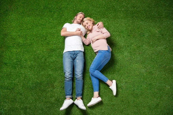 Pregnant woman with boyfriend lying on grass — Stock Photo