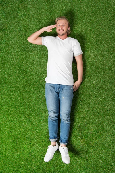 Uomo sdraiato con gesto di saluto sul prato — Foto stock