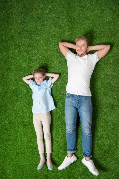 Pai com pequena filha relaxante na grama — Fotografia de Stock