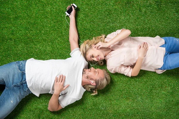Sweethearts listening music on grass — Stock Photo