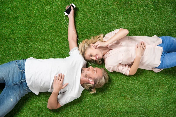 Novios escuchando música en la hierba - foto de stock