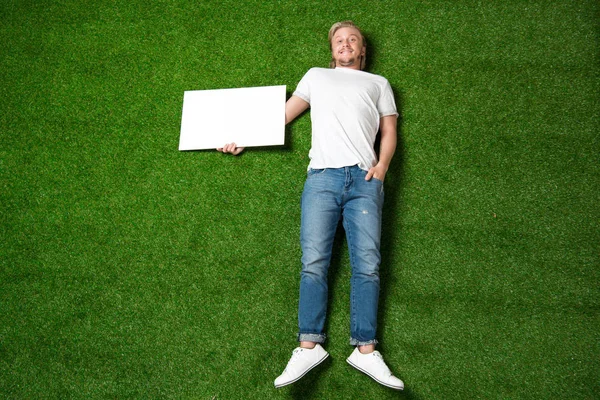 Людина з порожнім плакатом на траві — стокове фото
