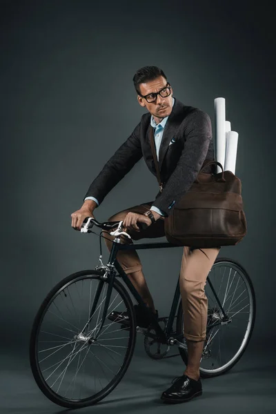 Confident businessman with bag riding on bicycle — Stock Photo, Image