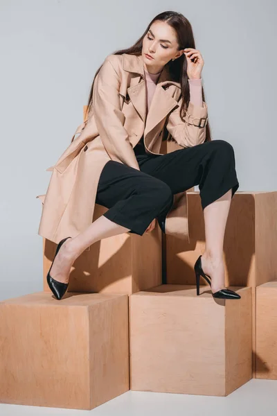 Fashionable woman sitting on wooden blocks — Stock Photo, Image
