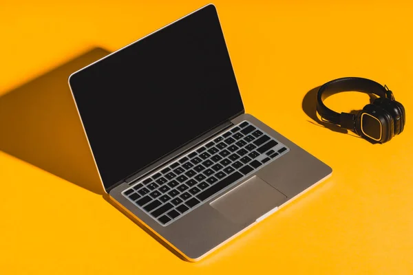 Hoofdtelefoons en laptop met leeg scherm — Stockfoto