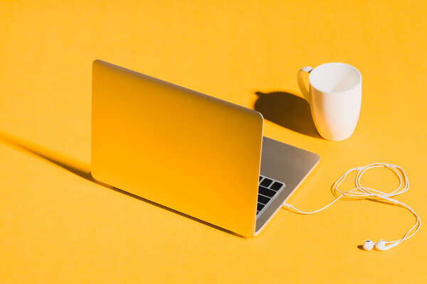 laptop, earphones and coffee cup