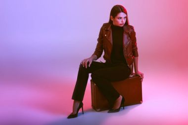 Kız bavulun üzerinde oturuyor.