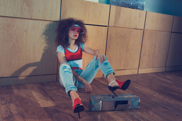 fashionable woman with boombox sitting on floor
