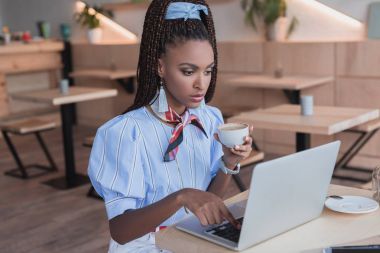 Kafede dizüstü bilgisayarla çalışan bir kadın.