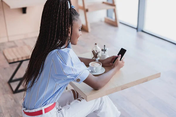 African american woman using smartphone in cafe — Stock Photo, Image