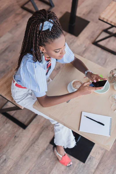 Αφρικανική αμερικανική γυναίκα χρησιμοποιώντας το smartphone στο καφέ — Φωτογραφία Αρχείου