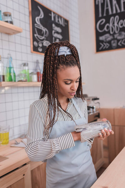 бариста вытирает стекло полотенцем
