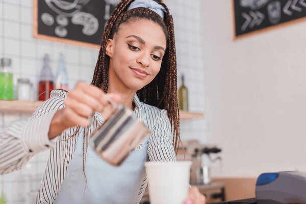 barista pouring milk into coffee