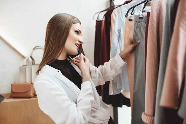 Woman with smartphone choosing clothes — Stock Photo, Image