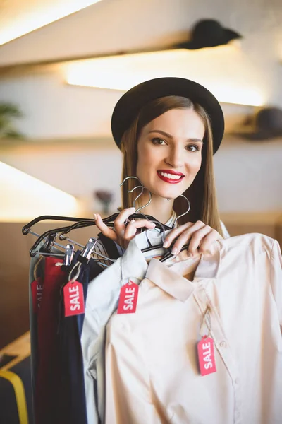 Girl holding clothes with sale tags — Stock Photo, Image