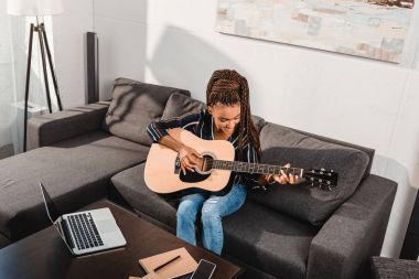  woman playing guitar on couch clipart