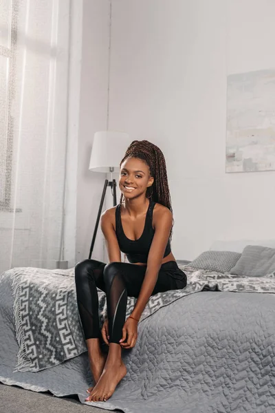 Frau in Sportbekleidung sitzt auf Bett — Stockfoto