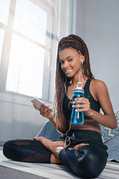 Mulher esportiva com smartphone e garrafa de água — Fotografia de Stock