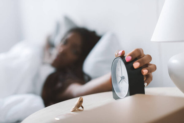 woman turning alarm clock off