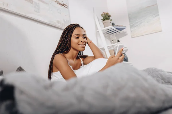 Mujer usando smartphone en la cama — Foto de Stock