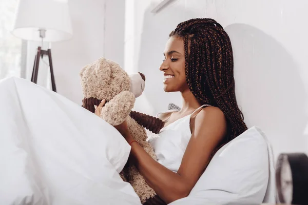 Mujer con oso de peluche en la cama — Foto de Stock
