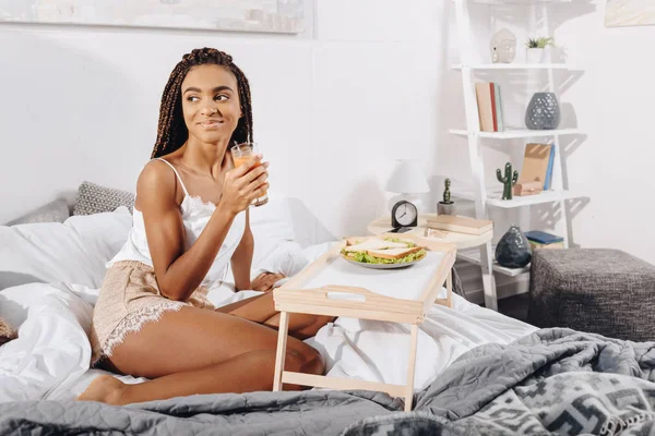 Wanita dengan jus dan sandwich di tempat tidur — Stok Foto