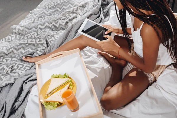 Mulher com café da manhã na cama usando tablet — Fotografia de Stock