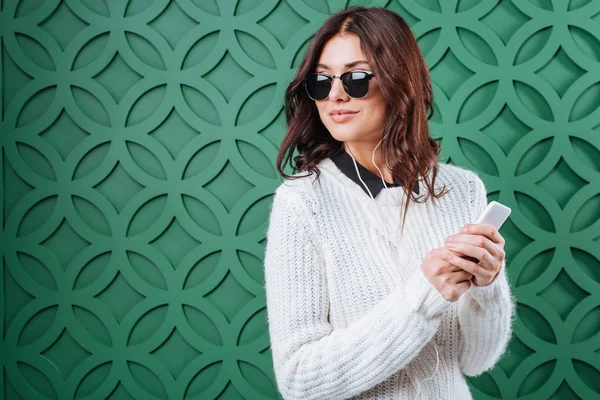 Woman in sweater and sunglasses listening to music — Stock Photo, Image