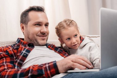 Baba ve kızı dizüstü bilgisayar kullanıyor.