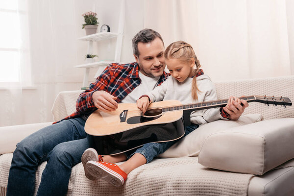 father and daughter playing guitar
