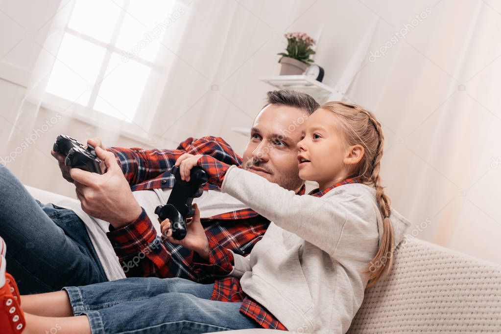 father and daughter playing with joysticks