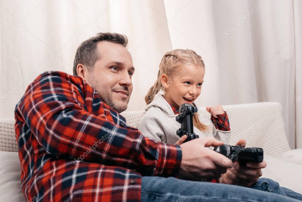 father and daughter playing with joysticks