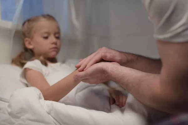 Father and daughter holding hands at bedtime — Free Stock Photo