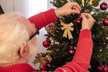 senior man decorating christmas tree clipart