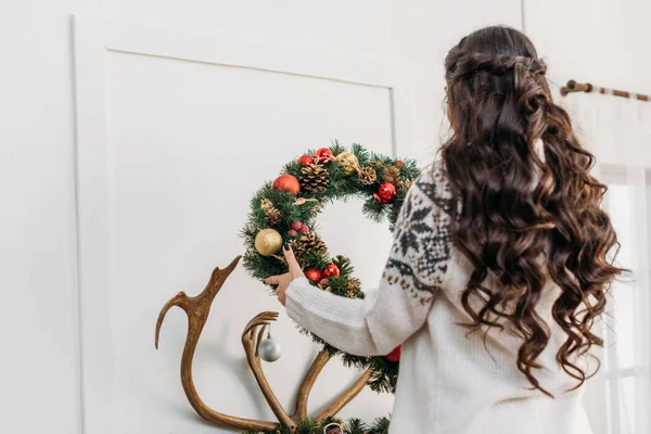 Woman hanging christmas wreath over fireplace — Stock Photo, Image