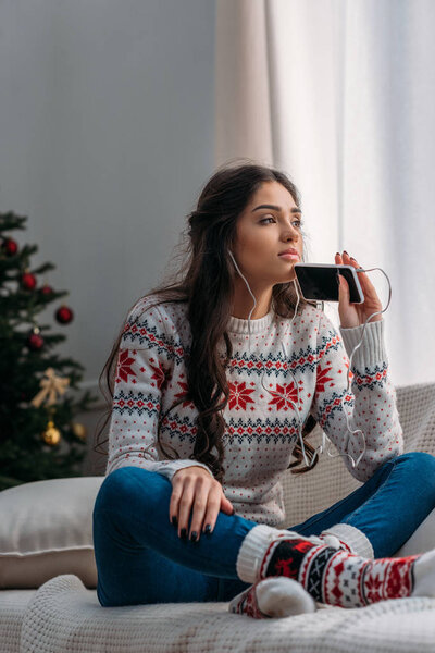 woman listening music in earphones on christmas
