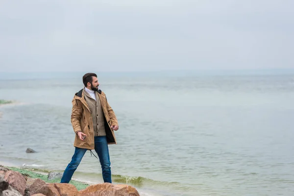 Man throwing stones into sea