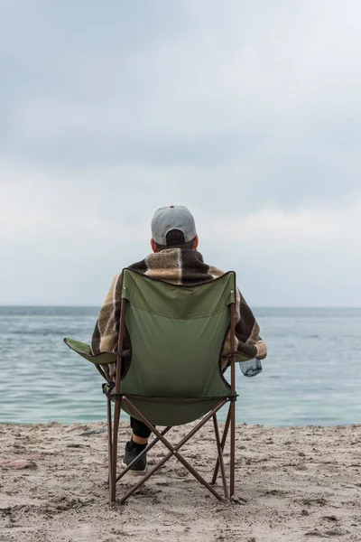 Man sitting on chair at seashore — Stock Photo, Image