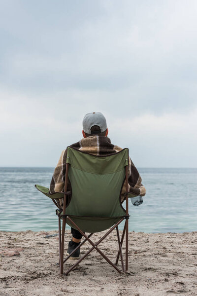man sitting on chair at seashore