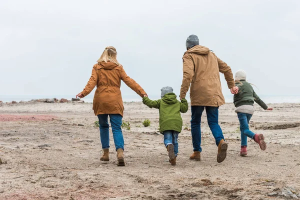 Family holding hands and walking by seashore — Stock Photo, Image