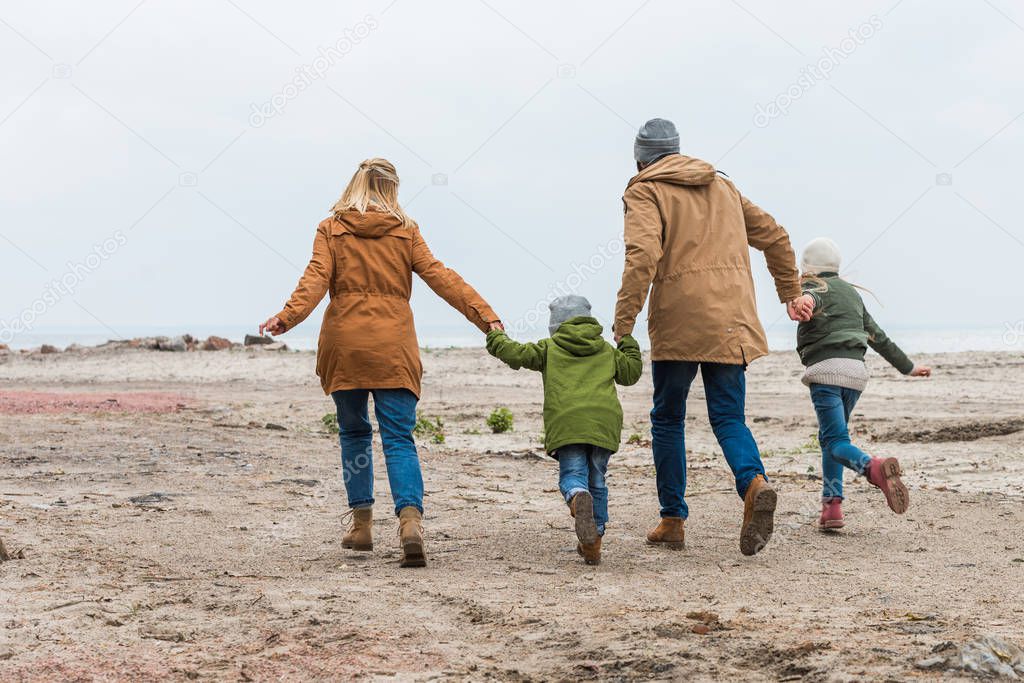 family holding hands and walking by seashore