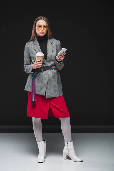 Женщина, стоящая со смартфоном и чашкой кофе — стоковое фото